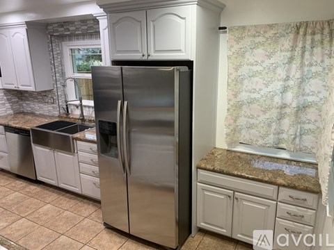 A kitchen with a stainless steel refrigerator and white cabinets.