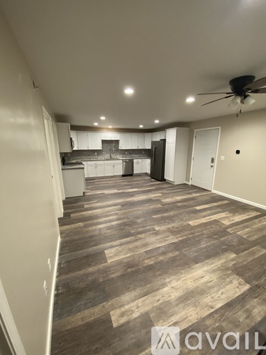 A spacious room with wooden flooring and a ceiling fan.
