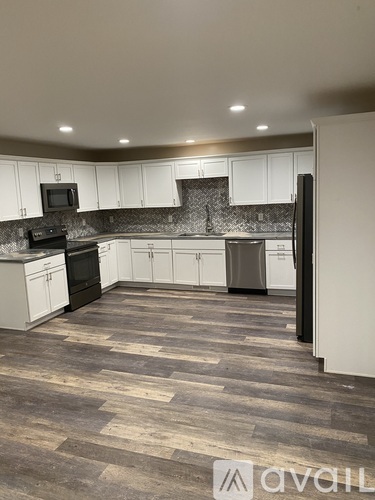 A kitchen with wooden flooring and white cabinets.
