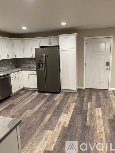 A kitchen with a refrigerator, cabinets, and a door.