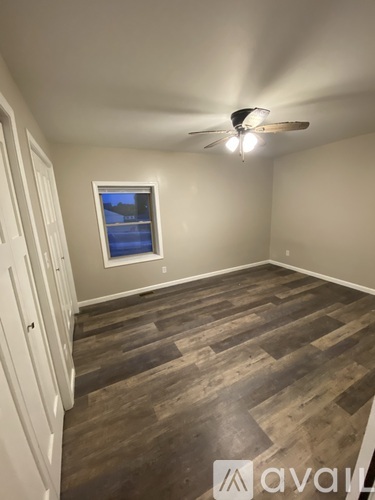 A room with wooden flooring and a ceiling fan.