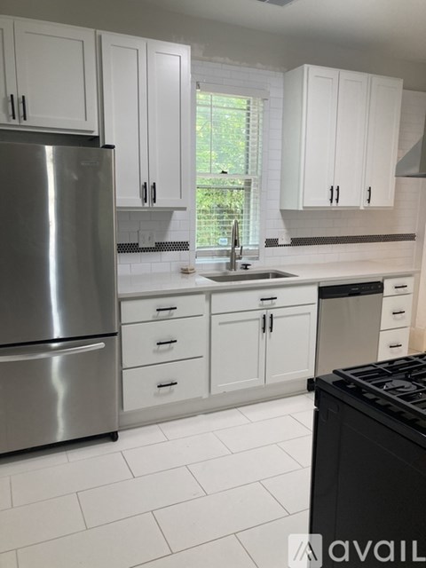 A kitchen with white cabinets and a stainless steel refrigerator.