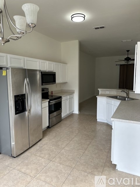 A kitchen with a stainless steel refrigerator and white cabinets.