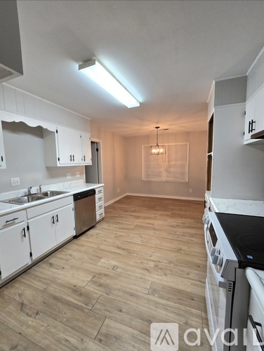 A kitchen with white cabinets and a wooden floor.
