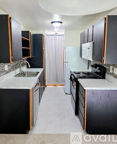 A kitchen with black cabinets and a white refrigerator.