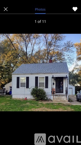 A small white house with a black roof and a porch.