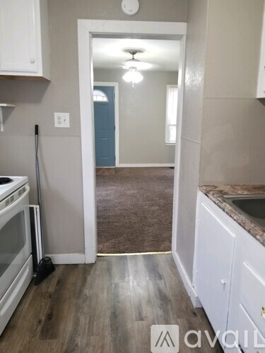 A kitchen with white cabinets and a wooden floor.