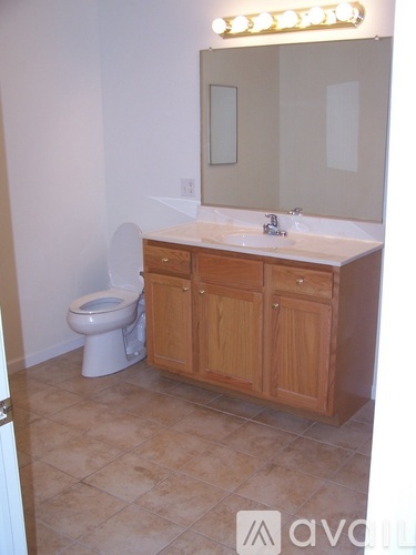 A bathroom with a toilet, sink and wooden cabinet.