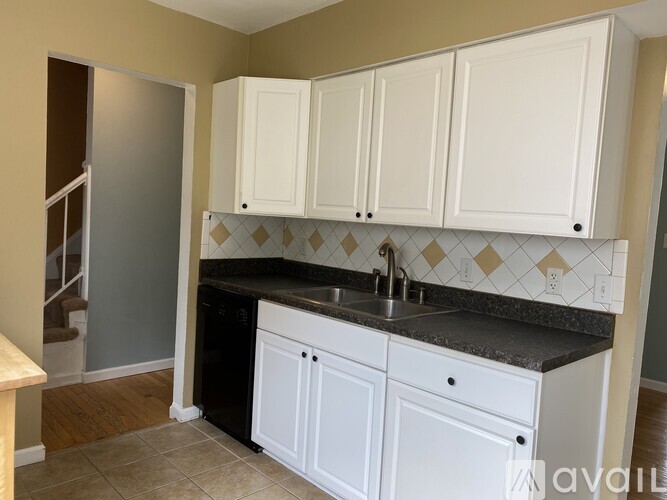 A kitchen with white cabinets and a black countertop.