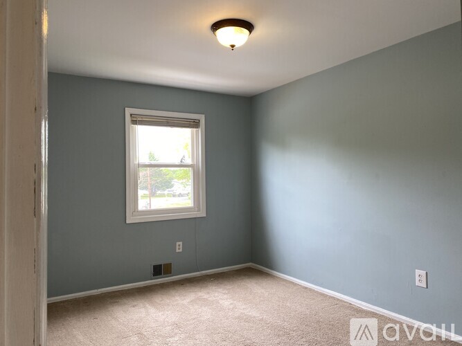 A room with a window and a carpeted floor.