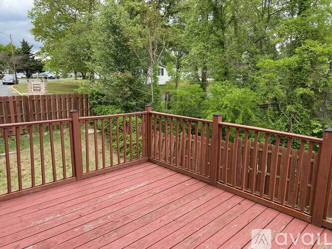 A wooden deck with a railing and trees in the background.