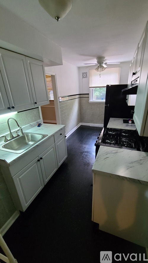 A kitchen with white cabinets and a black floor.