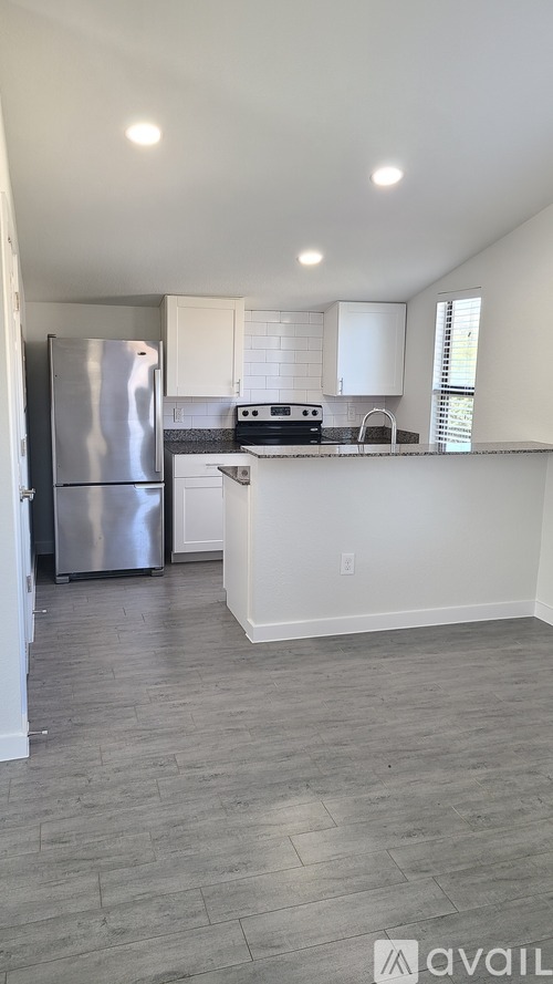 A kitchen with a refrigerator, stove, and cabinets.