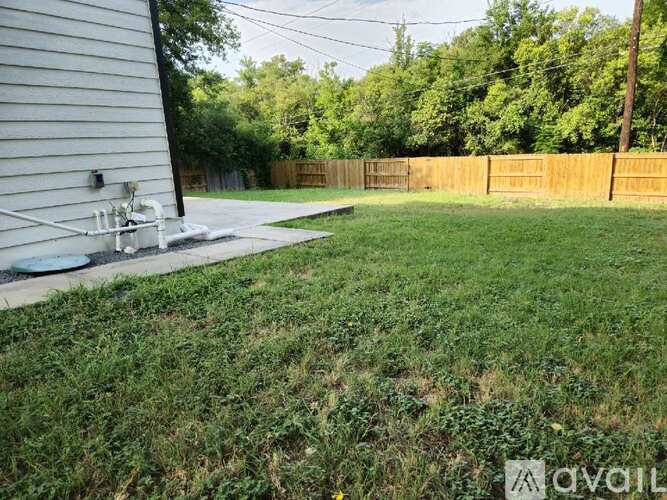 A backyard with a fence and a small patch of grass.