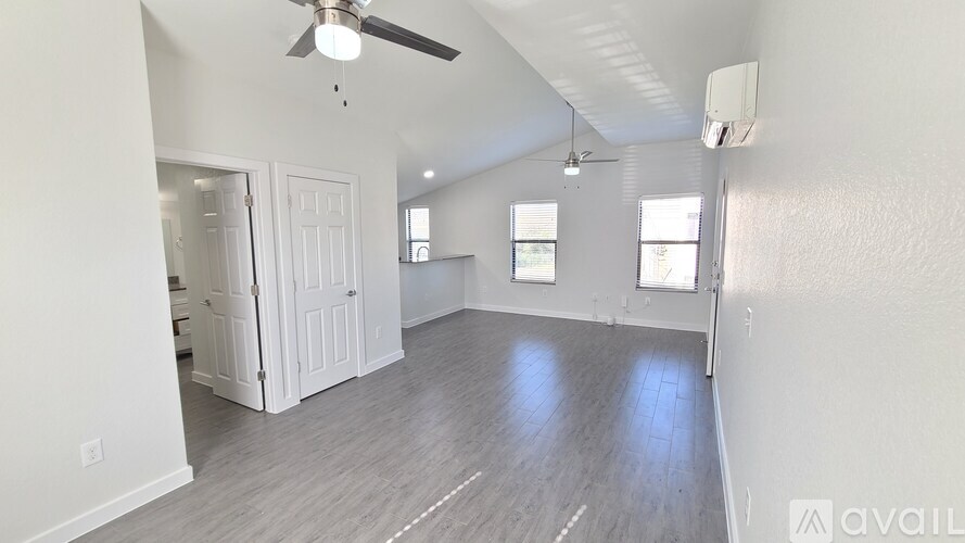 A spacious room with a ceiling fan and a door leading to another room.