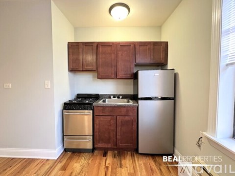 A kitchen with wooden cabinets and a stainless steel refrigerator.
