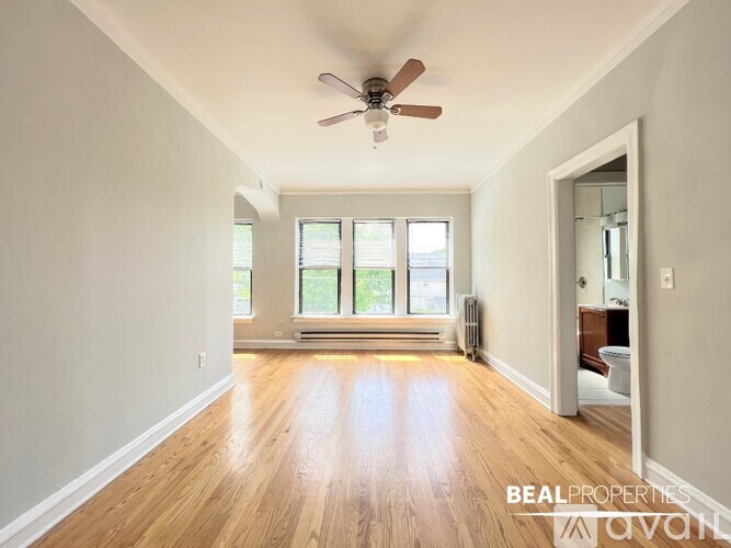 A spacious room with a ceiling fan and wooden flooring.