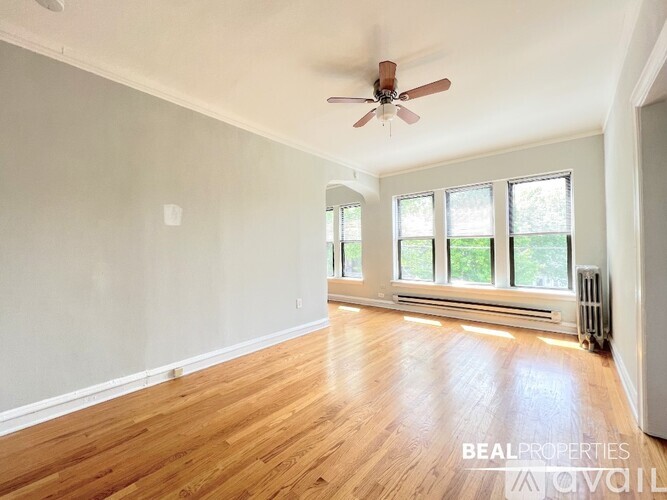 A room with a ceiling fan and wooden flooring.