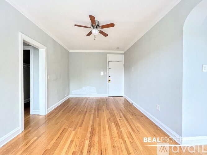 A room with a ceiling fan and wooden flooring.