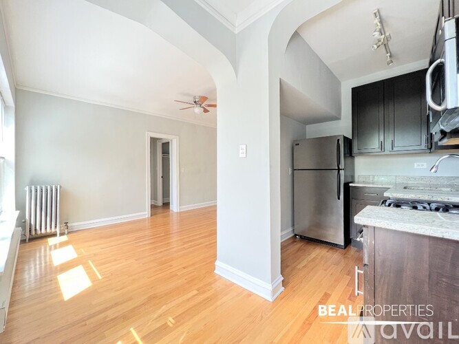 A kitchen with a stainless steel refrigerator and a wooden floor.