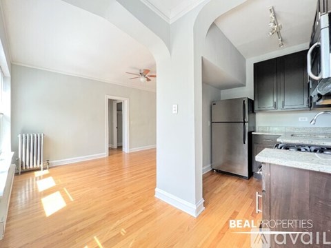 A kitchen with a stainless steel refrigerator and a wooden floor.