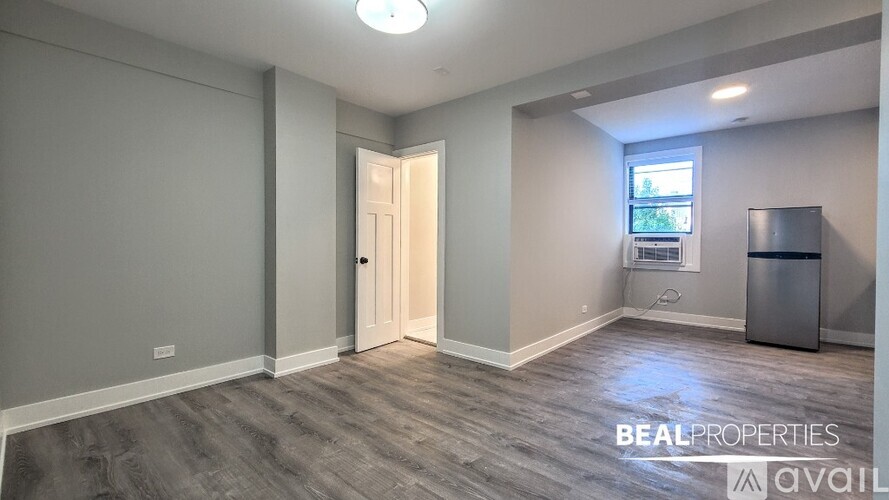 A room with a door and a window with a trash bin.