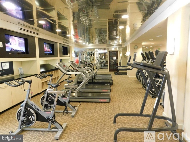 A gym with a row of stationary bikes and treadmills.