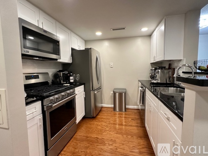 A kitchen with white cabinets and black appliances.