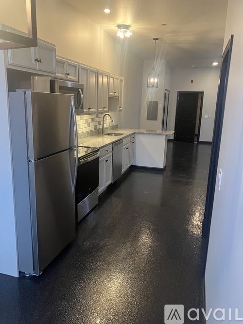 A kitchen with a stainless steel refrigerator and white cabinets.
