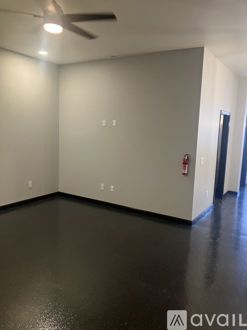A room with a ceiling fan and a door on the right side.