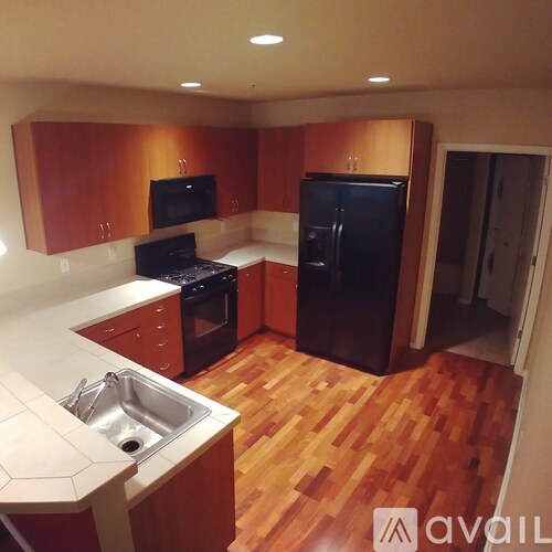 A kitchen with wooden floors and a black refrigerator.