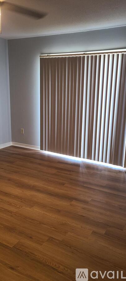 A room with wooden flooring and a window with blinds.
