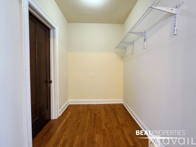 A room with a wooden floor and a white wall with a shelving unit.
