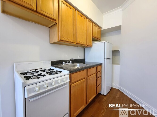 A kitchen with a white stove top oven and wooden cabinets.