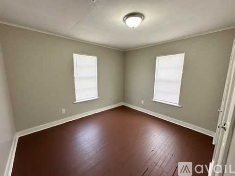 A room with wooden floors and two windows.