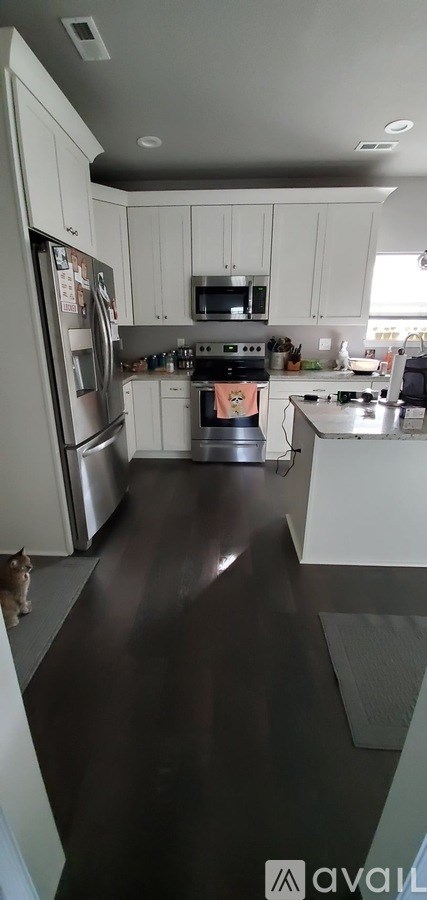 A kitchen with white cabinets and a stainless steel refrigerator.