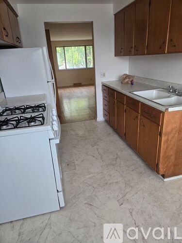 A kitchen with a white stove and wooden cabinets.