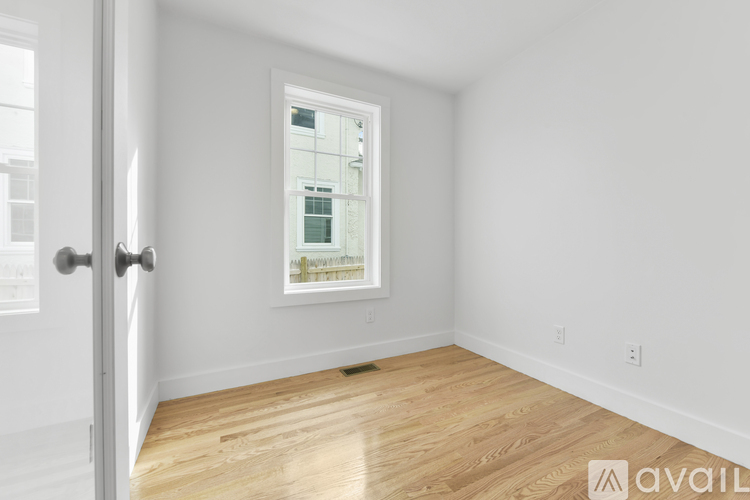 A room with a wooden floor and a window showing a view of a building.