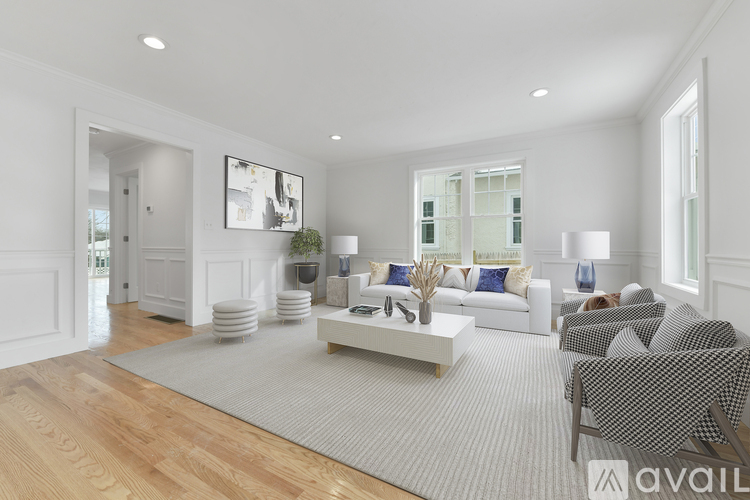 A living room with a white couch, a grey rug, and a wooden floor.