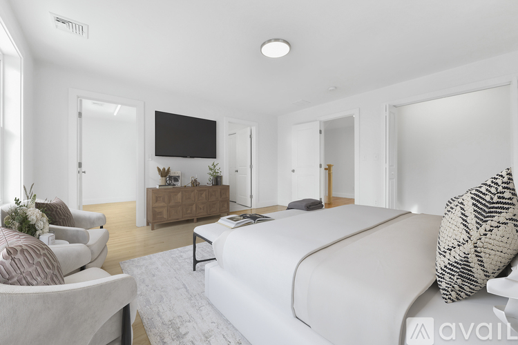 A modern bedroom with a large bed and a flat-screen TV mounted on the wall.