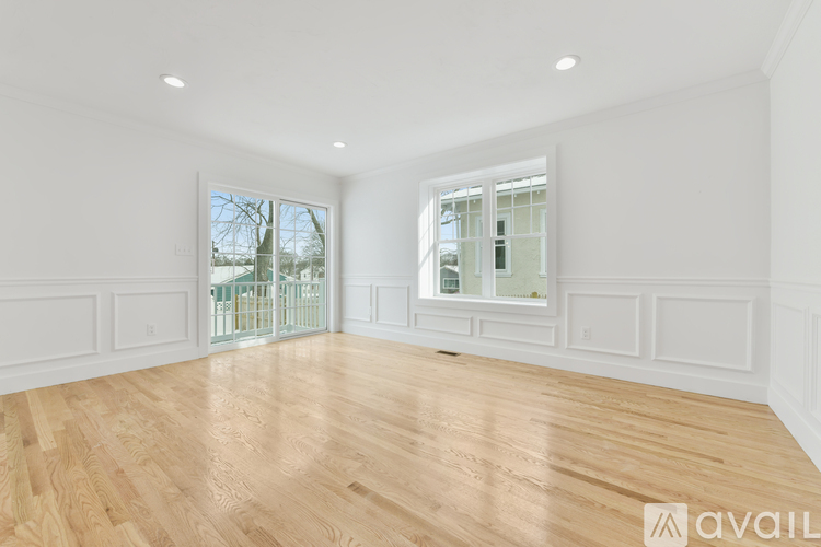 A spacious room with wooden flooring and white walls.