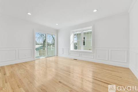 A spacious room with wooden flooring and white walls.