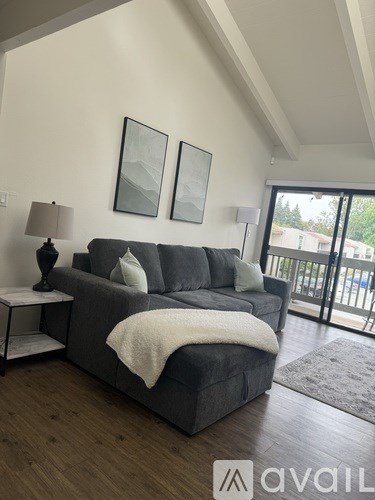A grey couch with a white blanket on it in a room with wooden floors.