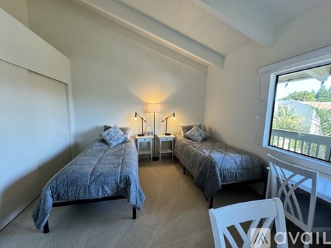 A bedroom with two beds and a chair.