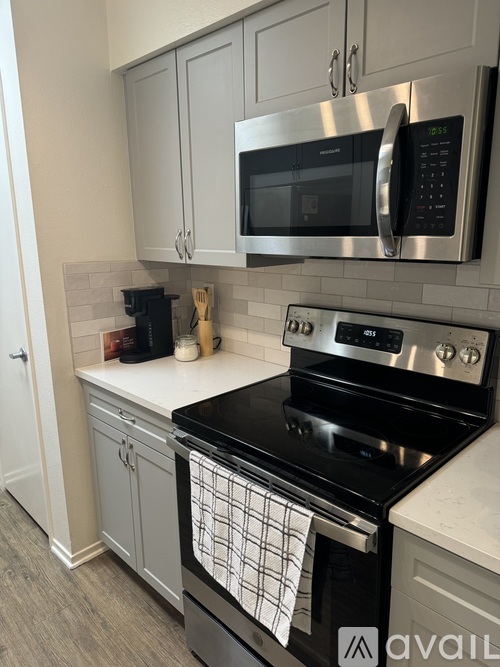 A modern kitchen with a black stove top oven and a silver microwave above it.
