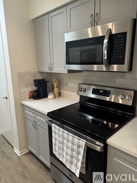 A modern kitchen with a black stove top oven and a silver microwave above it.