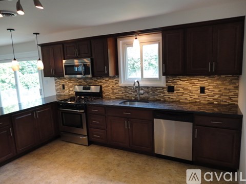 A kitchen with dark brown cabinets and a stone backsplash.