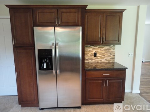 A stainless steel refrigerator with a water and ice maker sits in a kitchen with wooden cabinets.