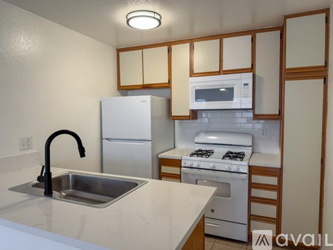A kitchen with a sink, stove, and refrigerator.