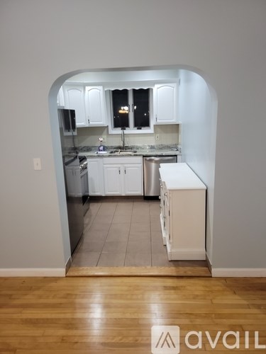 A kitchen with white cabinets and a wooden floor.